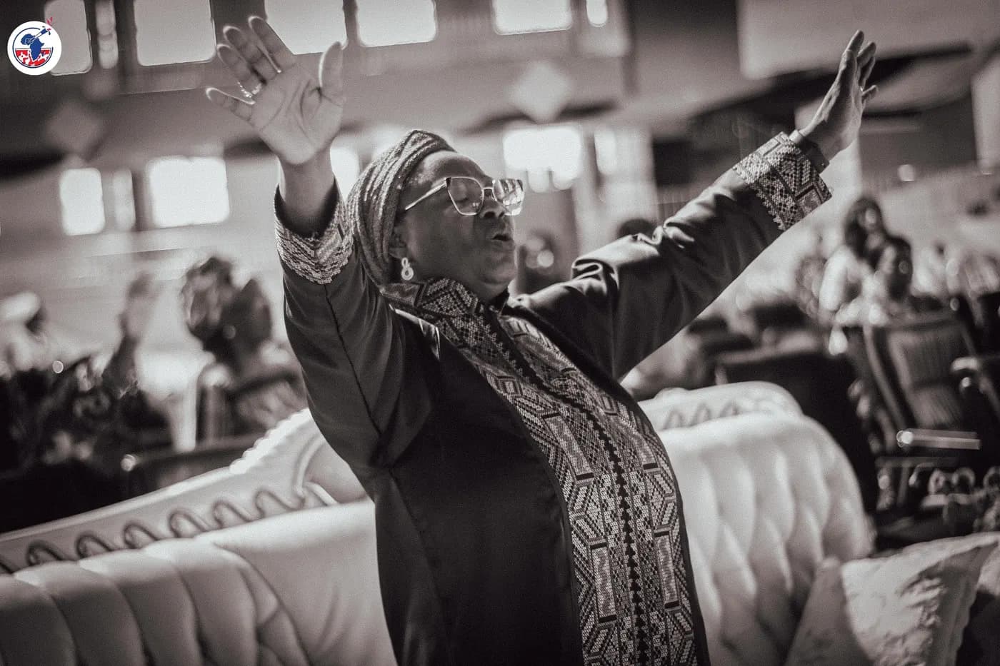 An elder in worship with her arms raised.