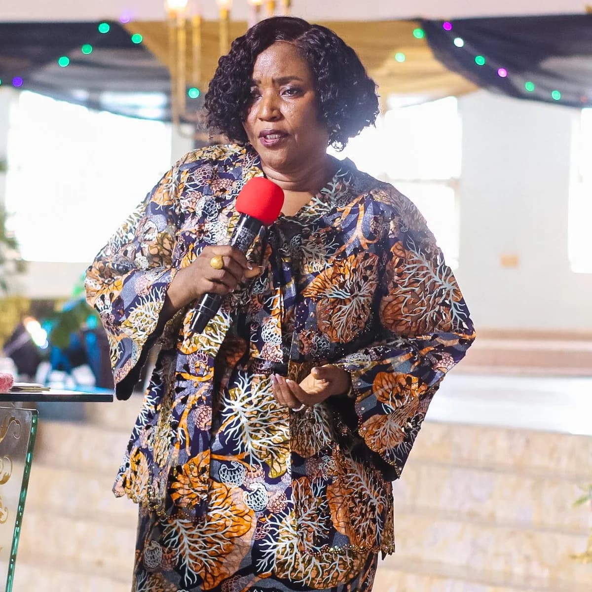 A woman addressing the WIGPA 25th anniversary gathering with composure and authority.